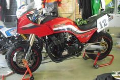 a red motorcycle parked inside of a garage next to other motorbike's