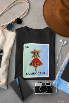 Embrace your heritage with our 'La Mexicana Loteria Shirt'! This vibrant tee celebrates Mexican pride and Latina beauty with its stunning Loteria card design. It's the perfect gift for any proud Latina, combining tradition and style flawlessly. Made with love and care, this Mexican pride shirt is sure to become a favorite in your wardrobe. To order, simply click the button and follow the easy steps. And to keep your shirt looking great, wash it with like colors and tumble dry on low. Elevate you Mexican Graphic Design, Loteria Shirts, Mexican Pride, Mexican Gifts, Mexican Breakfast, Shirts Diy, Latina Fashion, Adidas Outfit, Hand Embroidery Art