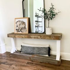 a wooden bench sitting next to a mirror on top of a wall near a potted plant