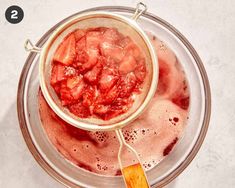 a glass bowl filled with liquid and strawberries