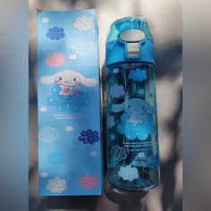 a blue water bottle sitting next to an empty box on a bed with clouds and clouds