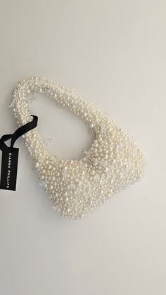 a white necklace with pearls and a black ribbon hanging from it's neckline