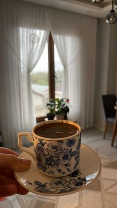 a cup of hot chocolate sitting on top of a saucer in front of a window