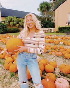 a woman is standing in front of pumpkins