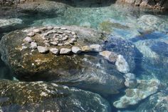 some rocks in the water and one is sitting on top of it with a circular rock