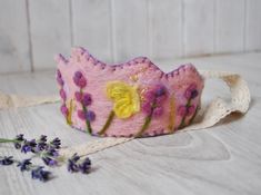 a pink and yellow flowered crown sitting on top of a white table next to lavender flowers