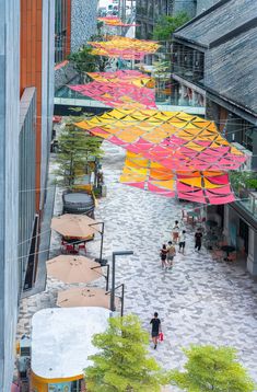 an overhead view of people walking and sitting on the ground in front of umbrellas