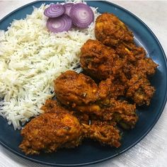 a blue plate topped with rice and meat next to onion slices on top of it