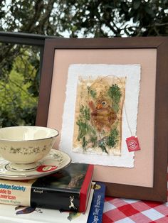 a cup and saucer sitting on top of a table next to a book with an image of a bird