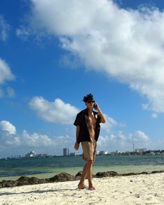 a man walking on the beach talking on his cell phone