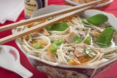 a bowl filled with noodles, meat and veggies next to chopsticks