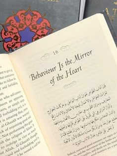 an open book with arabic writing on it and two other books in the back ground