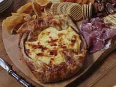 an assortment of cheeses, meats and crackers on a wooden platter