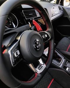 the interior of a car with red stitching and black leather trims, including steering wheel