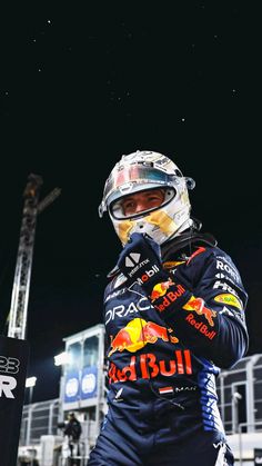 a man in a racing suit and helmet standing on the side of a race track