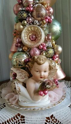 an angel figurine sitting on top of a christmas tree with ornaments around it