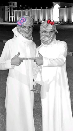 two men dressed in white standing next to each other with red hearts on their foreheads