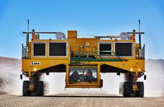 a large yellow truck driving down a dirt road