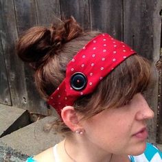 a woman is wearing a red headband with black buttons on it and her hair in a bun