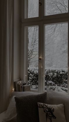 a white couch sitting in front of a window filled with snow covered trees and lights