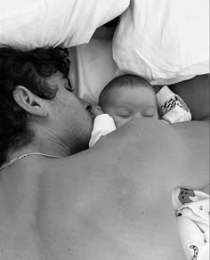 a man laying on top of a bed next to a baby