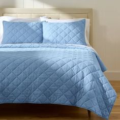 a bed with blue comforter and pillows on it