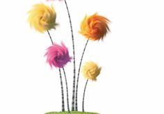 three colorful flowers in a vase with grass