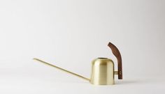 a gold watering can with a wooden handle