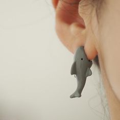 a close up of a person's ear with a dolphin earrings attached