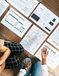 two people sitting on the floor with their feet up in front of some paper diagrams