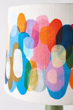 a lamp shade with colorful circles on it and a white background that has been painted onto the lampshade