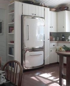 a white refrigerator freezer sitting inside of a kitchen next to a table and chairs