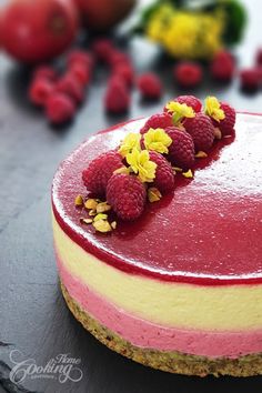 a raspberry cheesecake on a black table with berries and flowers around it