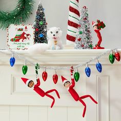 christmas decorations are displayed on the mantel in front of a fireplace with elfs