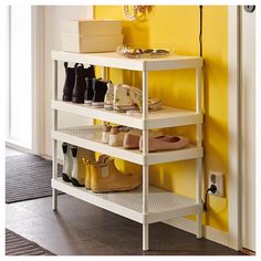 a white shelf with several pairs of shoes on it and a yellow wall in the background