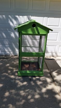 a green bird house sitting in front of a garage