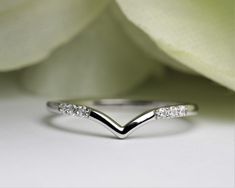 a white gold wedding band with three diamonds on the side, and a flower in the background