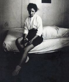 a black and white photo of a woman sitting on a bed with her legs crossed