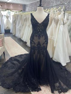 a black dress is on display in a bridal room with other wedding gowns