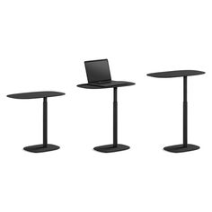 three black tables with laptops on them and one has a stand up desk top