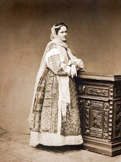 an old fashion photo of a woman standing next to a dresser with a veil on her head