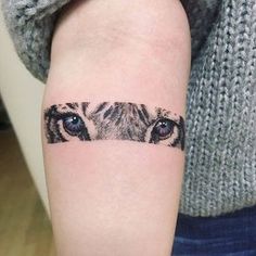 a woman's arm with a tiger eye tattoo on the left side of her forearm