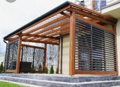 an outdoor covered patio with wooden slats and metal bars on the sides, in front of a house