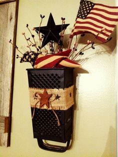 an american flag hanging on the wall next to a vase with flowers and stars in it