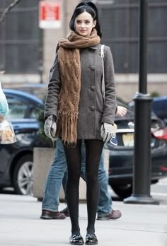 a woman walking down the street with a scarf around her neck