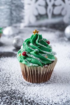 a cupcake covered in green frosting and topped with a christmas tree on top