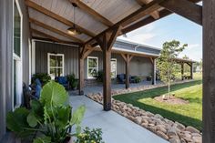 a covered patio with rocks and plants on the ground next to it is surrounded by greenery