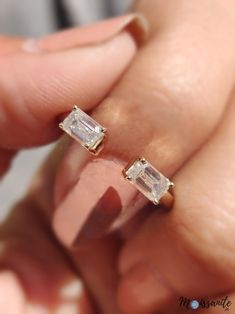 a woman's hand holding an engagement ring with two baguettes on it