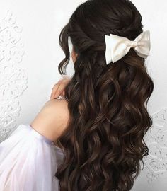 a woman with long brown hair wearing a white bow in her hair is looking at the wall