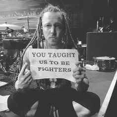 a man with dreadlocks holding up a sign that says you taught us to be fighters